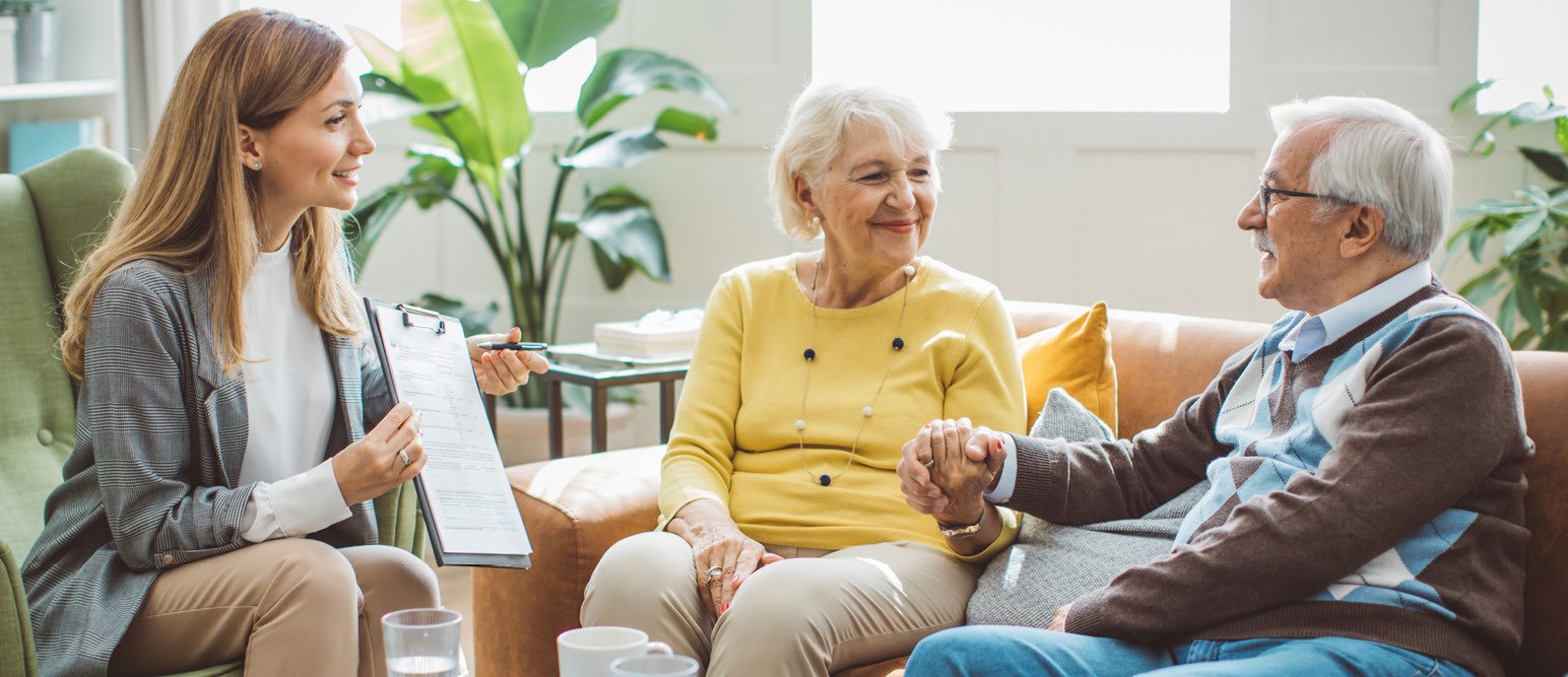 a female care provider sitting with a senior couple