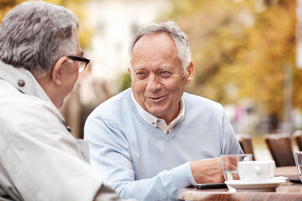 two senior men drinking coffee and laughing